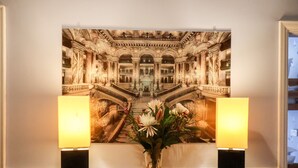 A framed architectural artwork on a wall, flanked by two illuminated lamps and a vase with flowers on a wooden table. - South Bay Beach House (Bridlington)