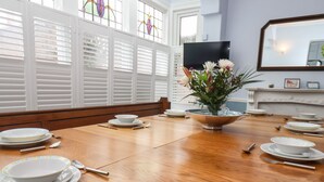 A dining table set with plates, bowls, and cutlery, with a flower vase in the center. - South Bay Beach House (Bridlington)