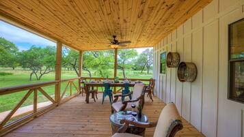 Relax in this serene outdoor space with a dining area, ceiling fan, and views of the surrounding grassy area.