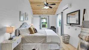 A bedroom with a bed, bedside table, lamp, and a ceiling fan. - Luxurious Cottage on 3-acre's in Fred Wine Country (Fredericksburg)