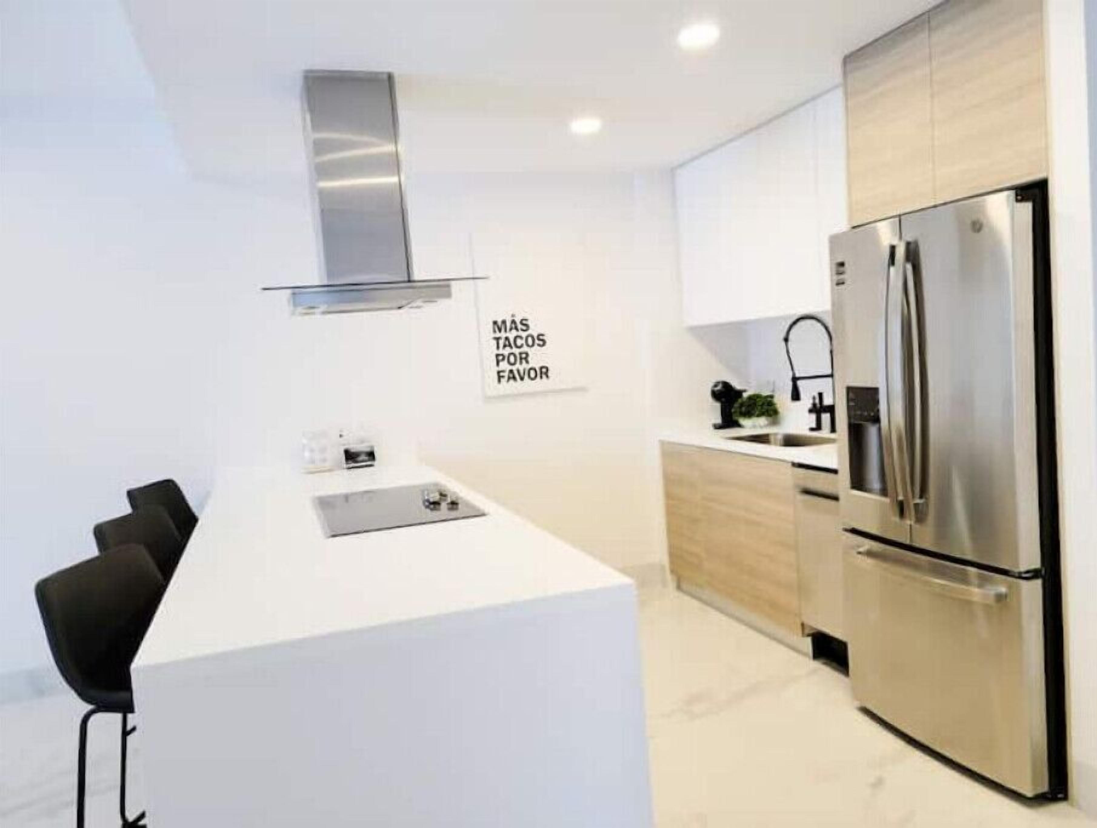 A modern kitchen with a stainless steel refrigerator, a built-in oven, and a white countertop.