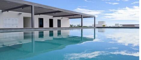 A modern building with a covered outdoor pool area and a clear blue sky.
