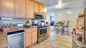A kitchen with wooden cabinets, stainless steel appliances, and a dining area with chairs and a table. - Centrally Located Hampton Home: 6 Mi to Downtown! (Hampton)