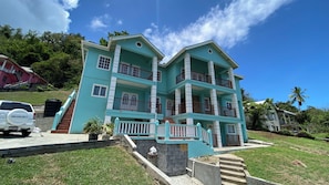 A multi-story building with balconies, a driveway, and a parked car. - Golden Palms Apartment - Modern, spacious, self-contained single Apartment (Diamond)