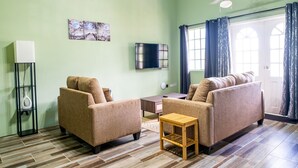 Una sala de estar con dos sofás, una mesa de centro, un televisor y un ventilador de techo.