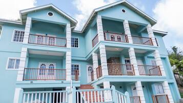 A multi-story building with balconies, windows, and a stone wall.