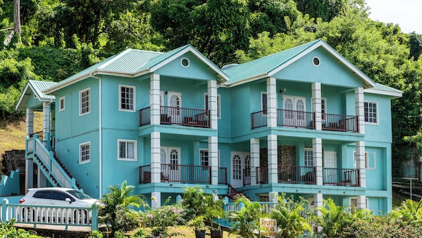 Un edificio de dos pisos con fachada azul claro, varios balcones y una escalera que conduce al piso superior.