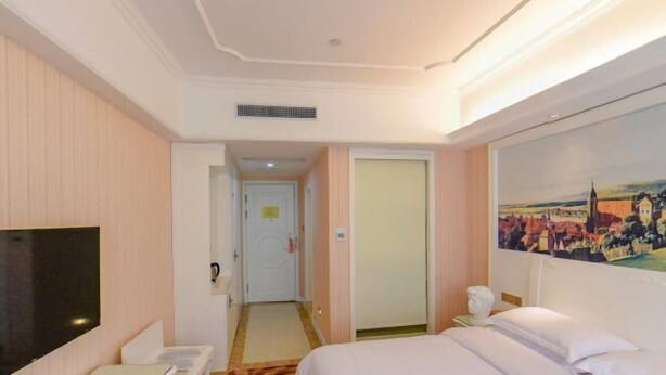 A hotel room with a bed, a TV, a desk, and a painting on the wall. - Fenghua Hotel (Ningbo)
