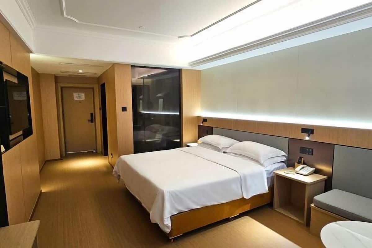 Une chambre d’hôtel avec un lit, une table de chevet et un petit bureau avec un téléphone.