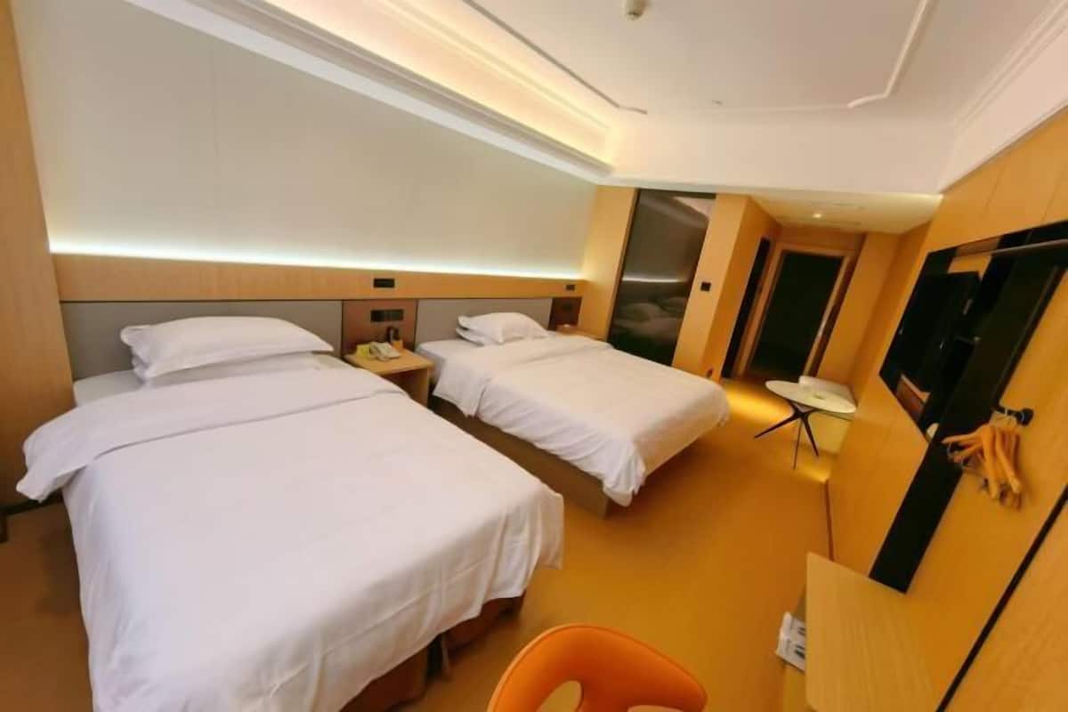 Une chambre d’hôtel avec deux lits, un bureau, une chaise et une télévision.
