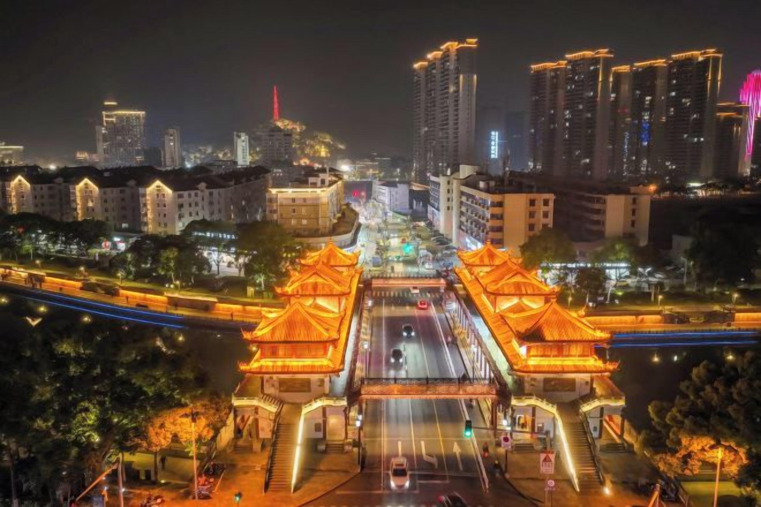 A night view of a cityscape with traditional architecture and modern buildings.