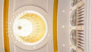 Een modern interieur met een ronde plafondlamp en een trap met witte leuningen.