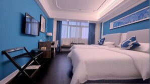 Een hotelkamer met twee bedden, een bureau, een stoel en een televisie aan de muur.