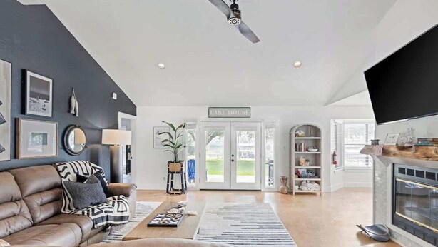 Ein geräumiges Wohnzimmer mit dunkler Akzentwand, einem Ledersofa, einem Couchtisch und einem Kamin.