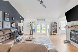 Uma sala de estar espaçosa com uma parede de destaque escura, um sofá de couro, uma mesa de centro e uma lareira.