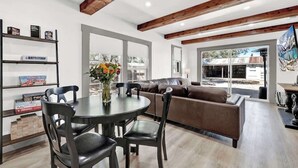 Una sala de estar moderna con una mesa de comedor, sillas, un sofá y una estantería.
