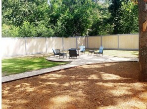 Un jardin avec un espace patio, du mobilier d’extérieur et une clôture en bois.