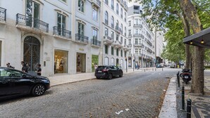 Eine Kopfsteinpflasterstraße gesäumt von historischen Gebäuden, ein schwarzes Auto parkte am Rand und ein Motorrad in der Nähe eines Baumes.