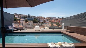 Ein Pool auf dem Dach mit Blick auf eine Stadtlandschaft, darunter Gebäude und ein Hügel.