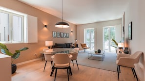 A modern living room with a glass coffee table, a sofa, and a dining area with chairs.