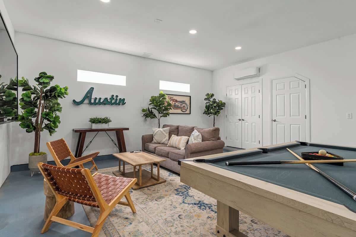 Un salon avec une table de billard, un canapé et deux fauteuils.