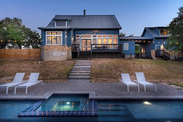 A house with a swimming pool, outdoor seating, and a well-lit entrance. - Luxurious Lake Park House: Sleeps 25, Pool, Hot-tub, Firepit and Game Room! (Dripping Springs)