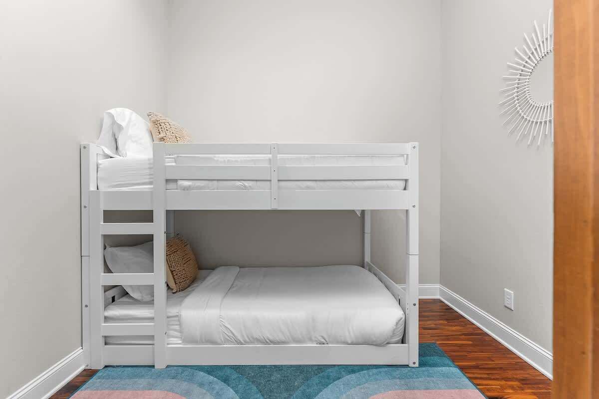 Een stapelbed in een kamer met een kamerbreed tapijt, een wandlamp en een houten vloer.