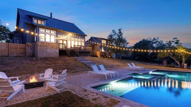 Ein Haus mit Swimmingpool, Sitzgelegenheiten im Freien und Lichterketten.