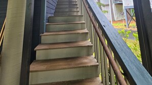 Una escalera de madera con barandilla que lleva a un porche cubierto.