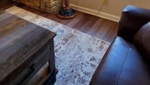 Una sala de estar con chimenea de piedra, un televisor montado arriba y una ventana con vistas a árboles.