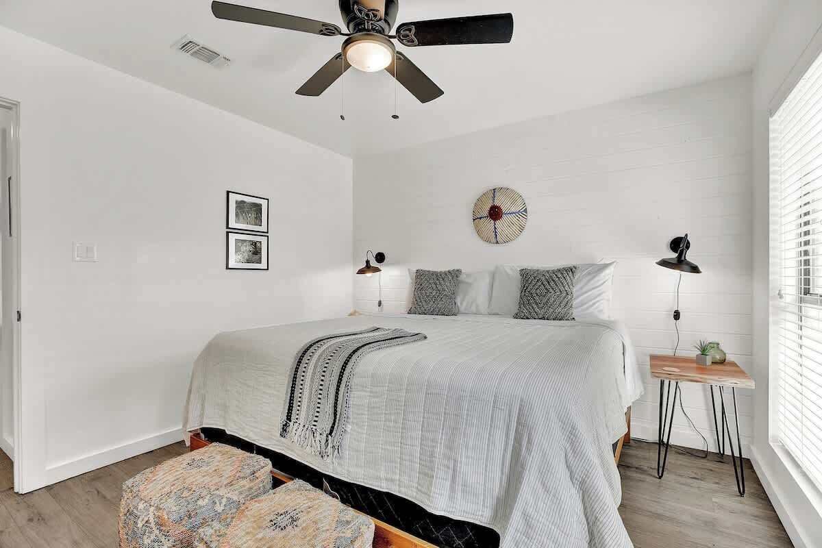 Une chambre à coucher comprenant un lit, un ventilateur de plafond, une table de chevet avec une lampe et une horloge murale.