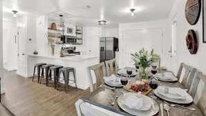 Una cocina moderna con armarios blancos, una isla central y taburetes de bar.