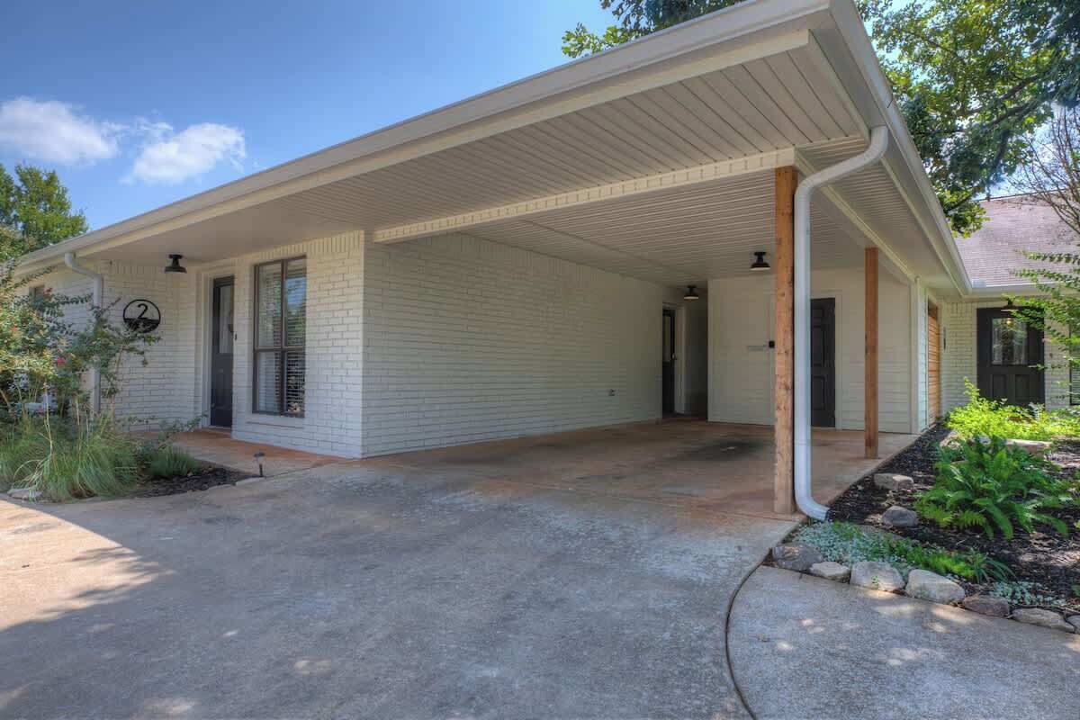 A single-story house with a covered porch, a brick exterior, and a front door.