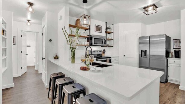Una cocina moderna con una isla grande, electrodomésticos de acero inoxidable y una zona con taburetes de bar.