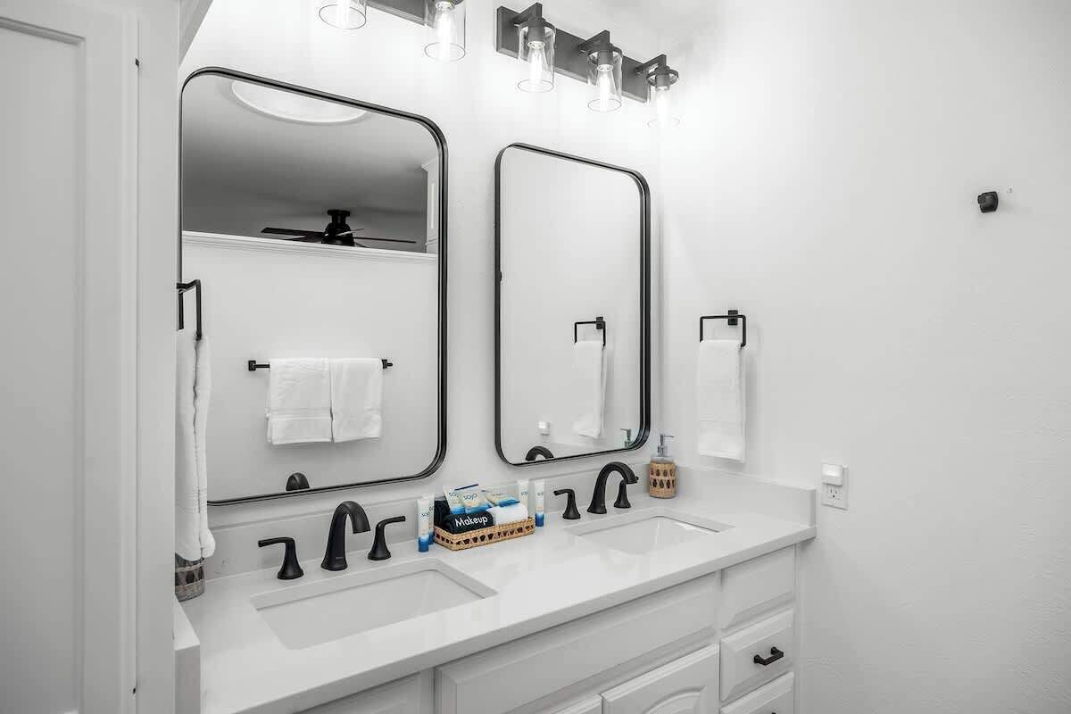 Een moderne badkamer met twee wasbakken, een grote spiegel en een wastafelmeubel met lades.
