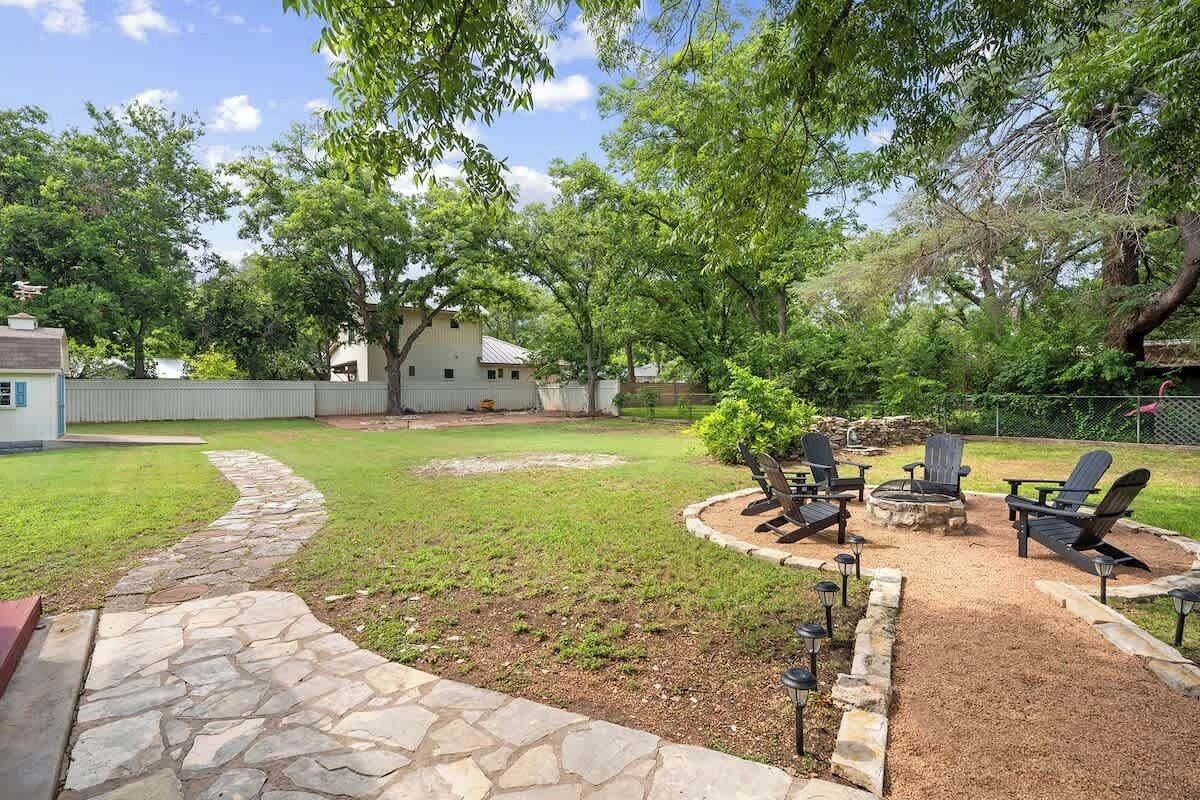 A backyard with a stone pathway, a fire pit, and outdoor seating.