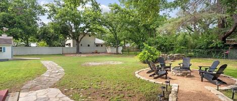 A backyard with a stone pathway, a fire pit, and outdoor seating.
