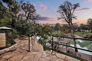 A stone staircase leading to a wooden deck overlooking a body of water, with benches and a gazebo. - Luxury Lakefront Oasis With Boat Dock-firepit (Seguin)