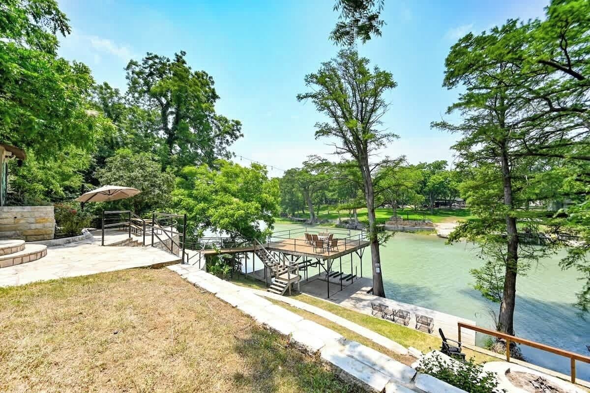 A lakeside deck with outdoor seating and a staircase leading to a wooden platform.