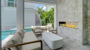 Un área exterior moderna con piscina, asientos cómodos y una chimenea integrada.