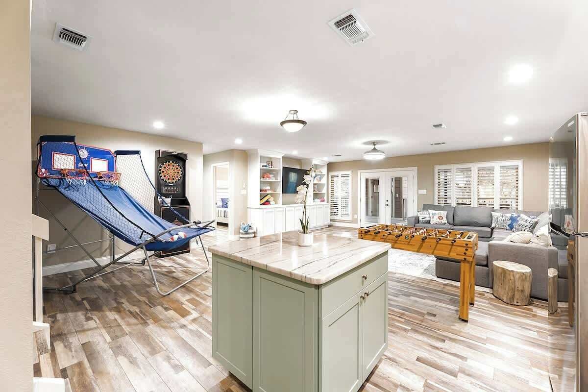 Un espacio habitable amplio con mesa de fútbol, tobogán azul y aro de baloncesto.