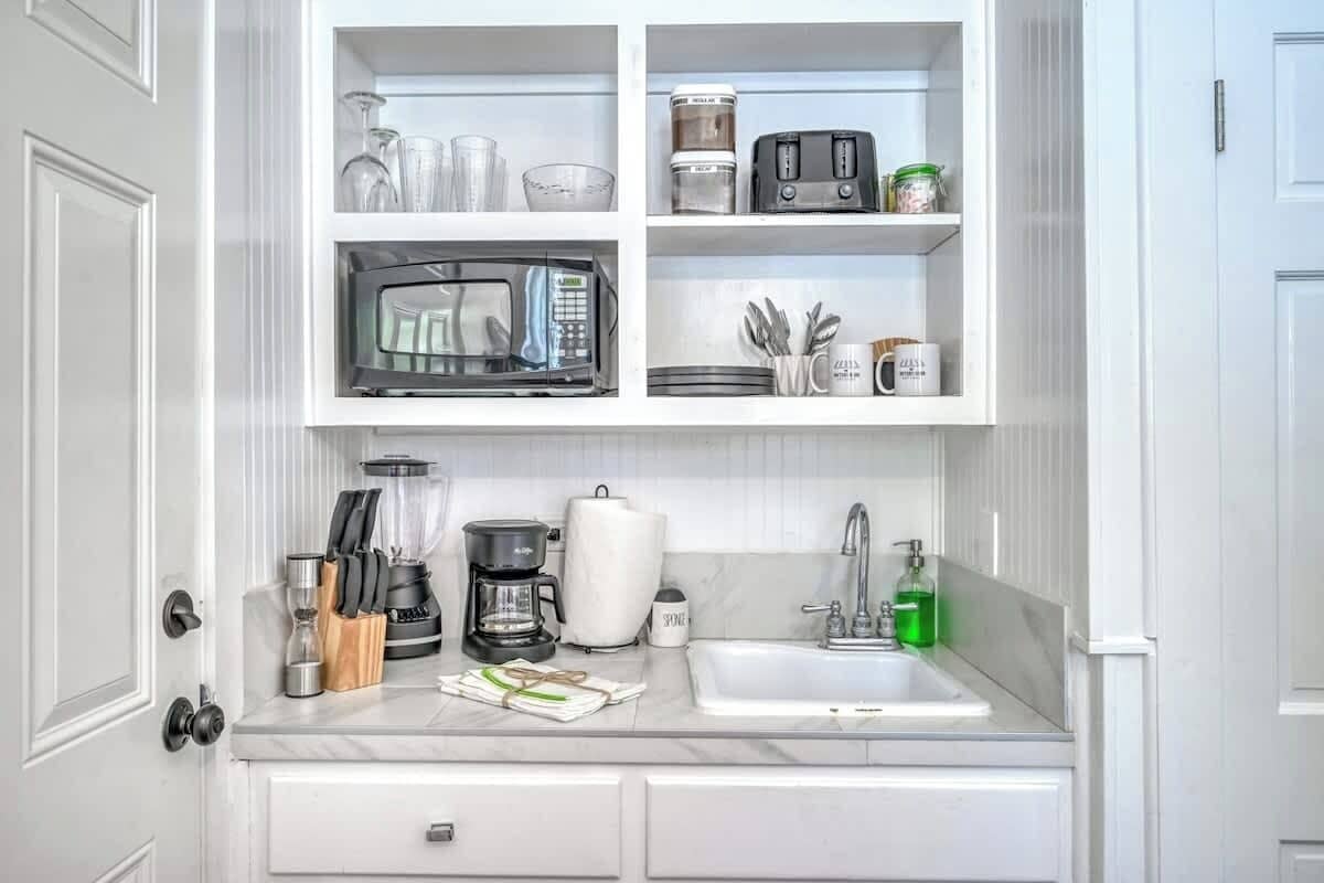 A kitchen with a built-in microwave, coffee maker, and sink.