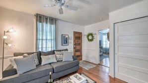 A living room with a grey sofa, a glass coffee table, and a ceiling fan. - Charming Cottage Near Main With Patio&firepit!! (Fredericksburg)