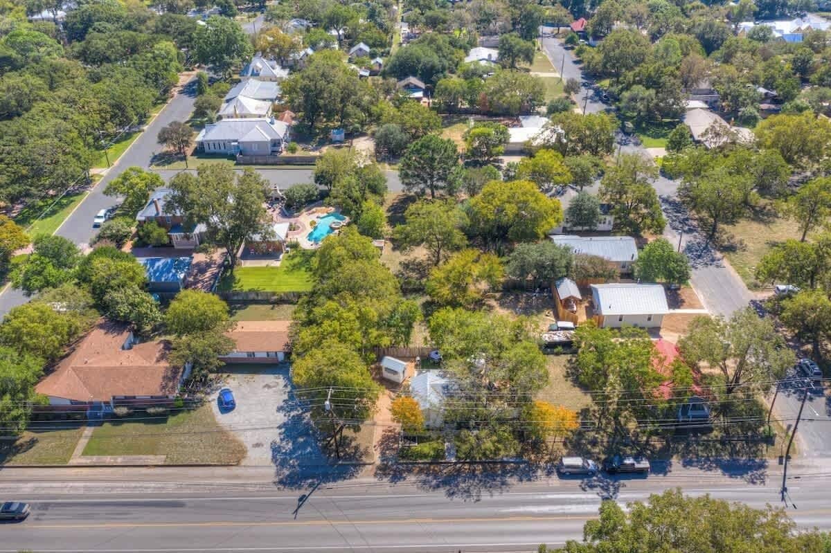 An aerial view of a residential area with houses, trees, and a road.