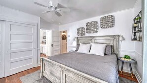 A bedroom with a bed, a ceiling fan, and decorative wall art. - Charming Cottage Near Main With Patio&firepit!! (Fredericksburg)