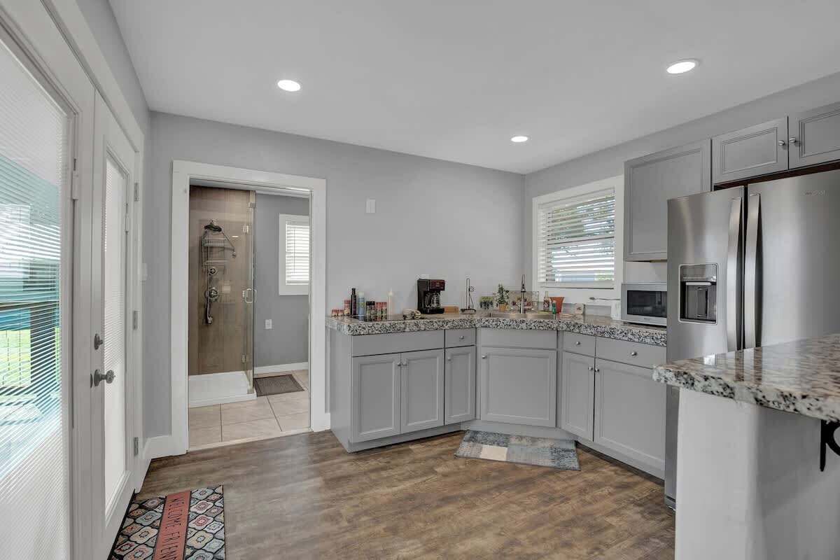 A modern kitchen with grey cabinets, stainless steel appliances, and a granite countertop.