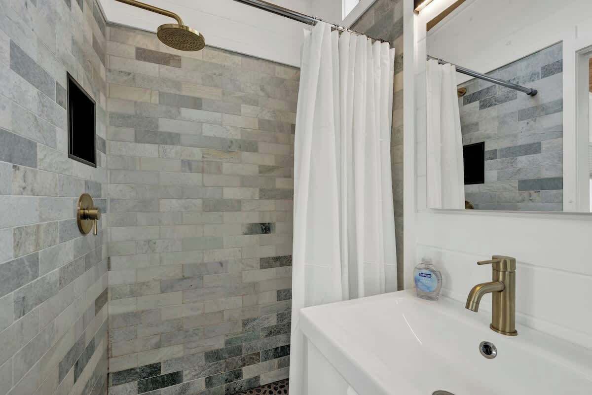 A bathroom with a shower, a sink, and a mirror.