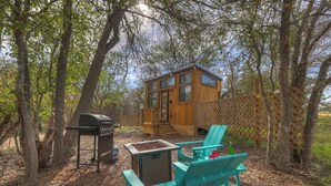 A wooden cabin with a deck, surrounded by trees.