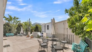 An outdoor patio area with a round table and chairs, a bench, and a street lamp. - Dreamy Downtown Condo, Near Meeting St & Broad St (Charleston)
