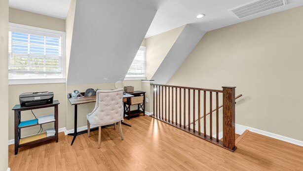 A room with a desk, chair, and a staircase with a wooden railing. - Dreamy Downtown Condo, Near Meeting St & Broad St (Charleston)